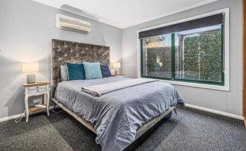 a bedroom with a large bed and a window at East Jindabyne- Cavallino 3 bedroom home in Jindabyne