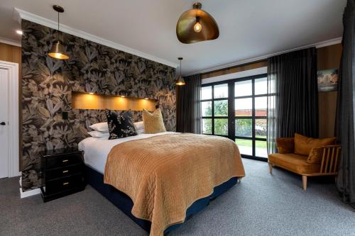 a bedroom with a large bed and a chair at The Deco Retreat in Hawera