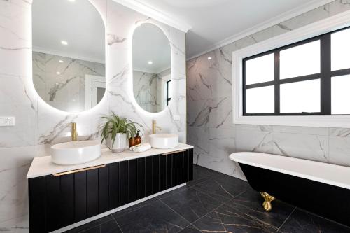 a bathroom with two sinks and a tub and mirror at The Deco Retreat in Hawera