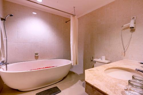 a bathroom with a white tub and a sink at Plagoo Holiday Hotel in Nusa Dua