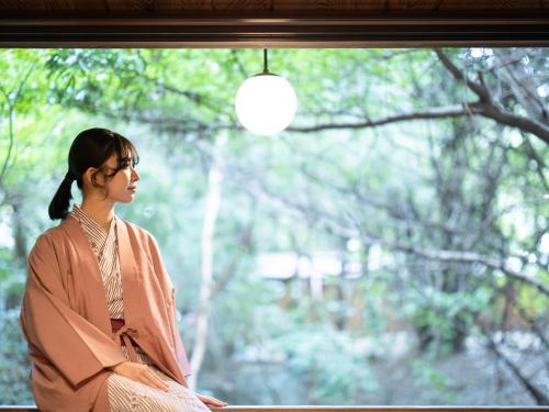 a woman is looking out of a window at Futsukaichi Hot Spring - Daimaru Besso in Chikushino