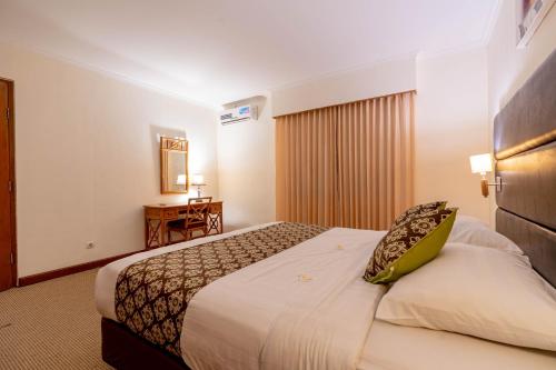a hotel room with a bed and a desk at Plagoo Holiday Hotel in Nusa Dua