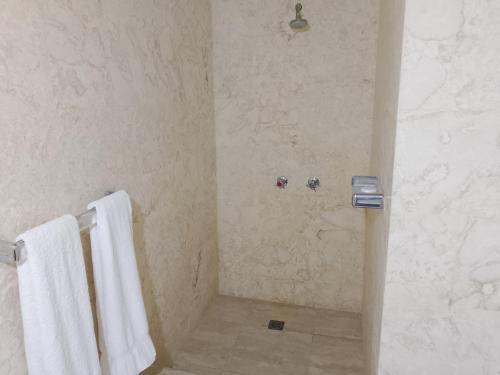 a bathroom with white towels and a shower at Hotel Garant & Suites in Boca Chica