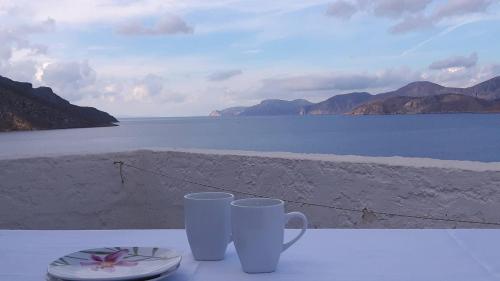 two cups on a table with a view of the water at Avra Studios in Masouri