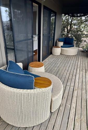 a deck with wicker chairs and tables on a house at Boutique Coastal Beach House Cowes Phillip Island Sleeps 8 in Cowes