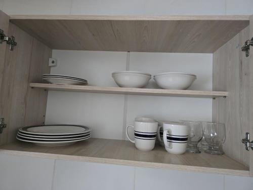 a kitchen shelf with plates and bowls and cups at Apart Ayres -Planta alta in Río Gallegos