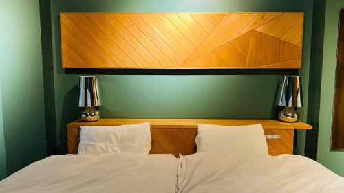 a bed with a wooden head board and two lamps at Onomichi SINGAI HOSTELS in Onomichi