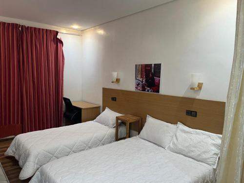 a hotel room with two beds and a red curtain at Résidence Meublée Jihane in Laayoune