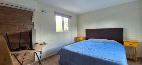 a bedroom with a bed and a desk with a television at Duplex Playa Mansa in Mina Clavero