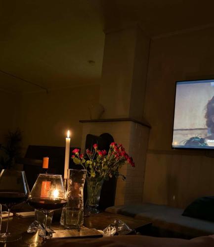 a table with a candle and flowers and a television at Koselig feriehus ved sjøen - Skjevikstranden in Steinkjer