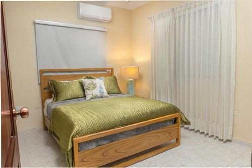 a bedroom with a bed with a green comforter at Villa Lionisia in Puerto Plata