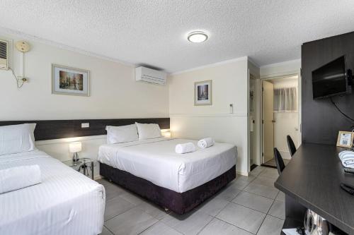 a hotel room with two beds and a desk at Gallery Motel in Murwillumbah