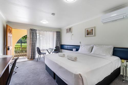 a hotel room with a large bed and a table at Gallery Motel in Murwillumbah