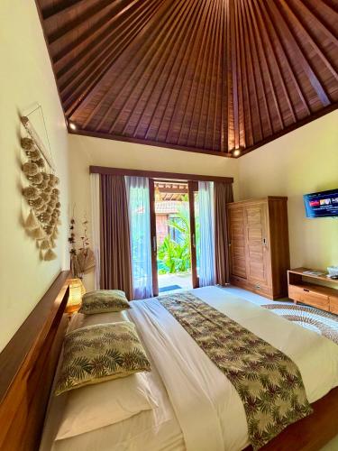 a bedroom with a large bed with a wooden ceiling at Cempaka Kembar Guest House Ubud in Ubud