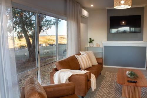 a living room with a couch and a large window at Bathurst Goldfields Resort - Conrod Straight, Mount Panorama in Bathurst