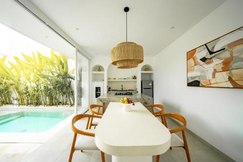 a dining room with a white table and chairs next to a pool at The Belluoccio Villa Pererenan in Tumbak Bayuh