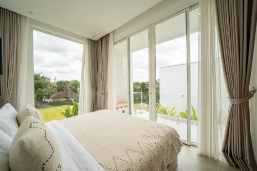 a bedroom with a bed and a large window at The Belluoccio Villa Pererenan in Tumbak Bayuh