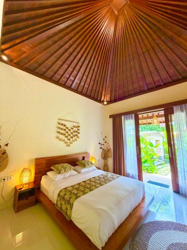 a bedroom with a large bed with a large roof at Cempaka Kembar Guest House Ubud in Ubud