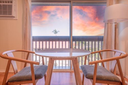 a table and two chairs in front of a window at Kailani Kona-Ocean view, top floor Downtown w pool in Kailua-Kona