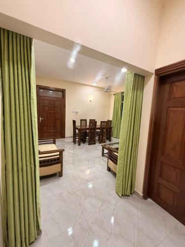 a room with green curtains and a table and chairs at Wellness Residency in Colombo