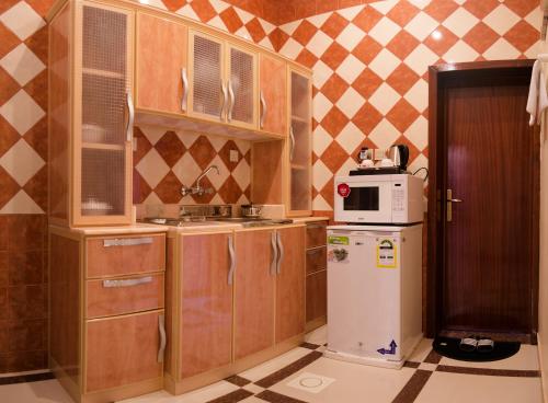 una pequeña cocina con armarios de madera y nevera. en Rose Palace For Residential Units, en Abha