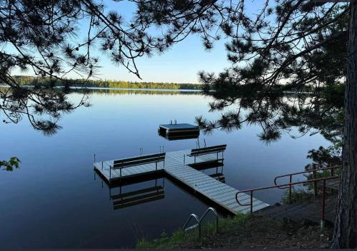 a dock on a lake with a boat in the water at Loons Landing Legacy in Saint Germain