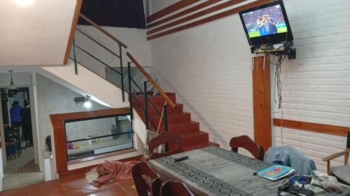 a living room with a table and a tv on the wall at Triplex waltito in San Clemente del Tuyu