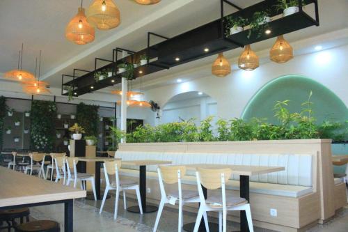 a restaurant with tables and chairs and potted plants at Hotel Mangkuto Syariah in Payakumbuh