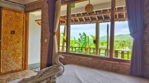 a bedroom with a bed and a large window at Metis Eco Lodge in Kuta Lombok