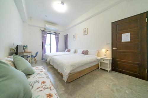 a bedroom with two beds and a wooden door at Sunlight Orchid Rain Homestay in Dongshan