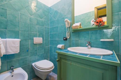 a blue tiled bathroom with a toilet and a sink at Albergo Residenziale Gli Ontani in Cala Liberotto