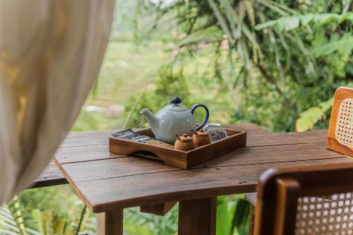 a tea pot and two cups on a wooden table at LeLangit Eco Cabin in Sidemen