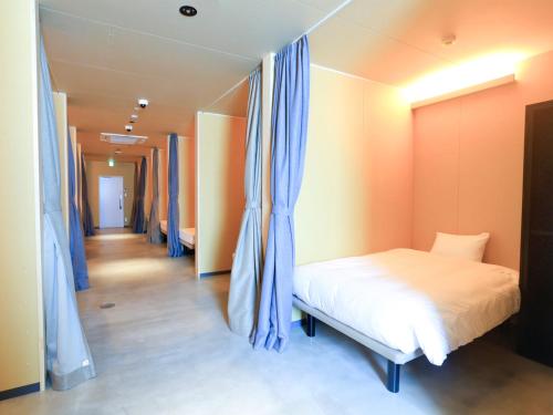 a room with a bed with blue curtains and a corridor at Cabin kutekun in Naka-shibetsu