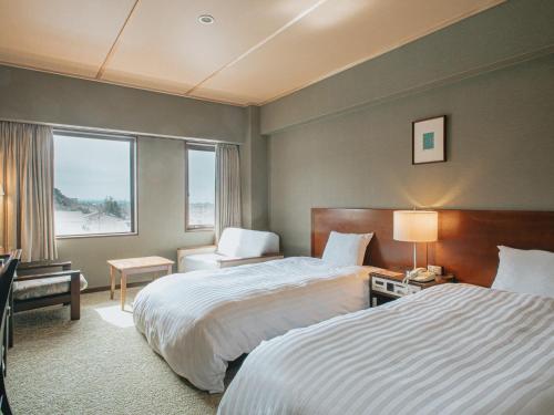 a hotel room with two beds and a window at Kanazawa Kokusai Hotel in Kanazawa