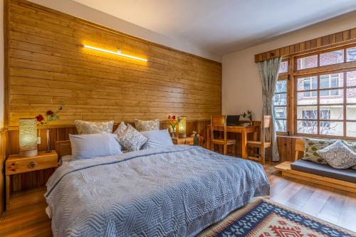 a bedroom with a bed and a wooden wall at Zeyul Homes in Manāli
