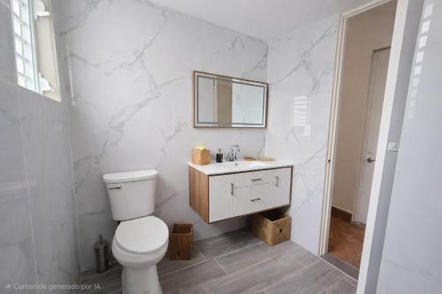 a white bathroom with a toilet and a mirror at Villa Zoed in San Juan