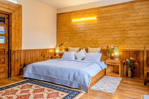 a bedroom with a bed with a wooden wall at Zeyul Homes in Manāli
