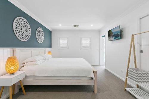 a bedroom with a white bed and a blue wall at Saltwater Cottage in Windang