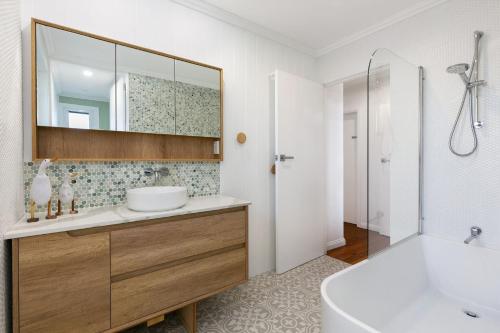 a bathroom with a sink and a mirror and a tub at Saltwater Cottage in Windang