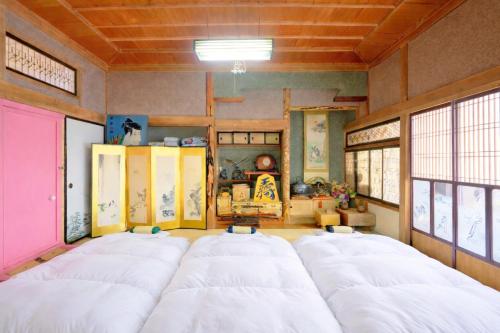 a room with four white beds in it at ラベンダー畑まで5分ー最大10人ーお餅つきー流しそうめんー花火ー五右衛門風呂ー心と身体が元気になる古民家民泊ーオモテナシロッジ悠遊 in Nakafurano