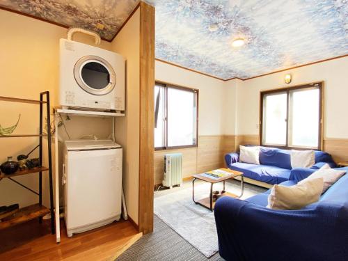 a living room with a blue couch and a microwave at Winterland Lodge & Taproom in Nozawa Onsen