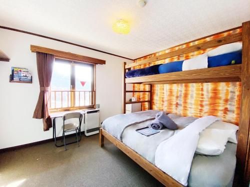 a bedroom with a bunk bed with a desk and a window at Winterland Lodge & Taproom in Nozawa Onsen