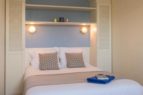 a bedroom with a bed with two pillows and lights at Residence Lacanau Bleu Marine - maeva Home in Lacanau