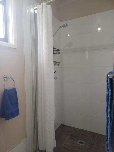 a shower with a white shower curtain in a bathroom at Wattleview in Lithgow