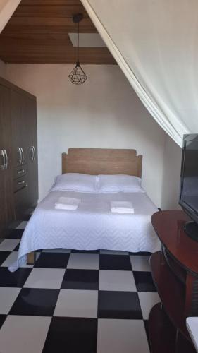 a bedroom with a bed and a checkered floor at Kitnet Duplex Ibiúna in Ibiúna