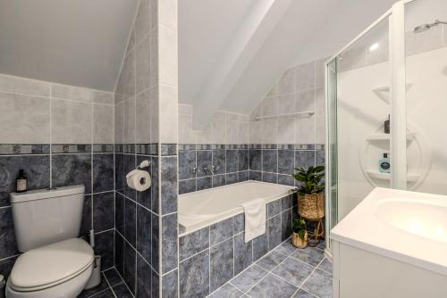 a bathroom with a toilet and a tub and a sink at The Canopy in Albany