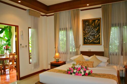 una camera da letto con un letto bianco con fiori sopra di Oriental Siam Resort - SHA Extra Plus Certified a Chiang Mai