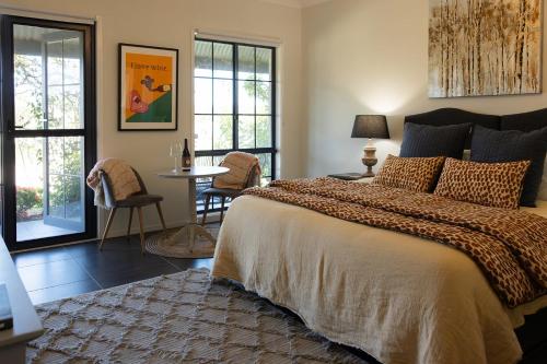 a bedroom with a bed and a table with chairs at Red Door Collective - RDC Vineyard Estate, Luxury Adult Only Stay in Pokolbin