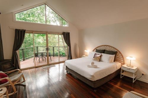 a bedroom with a large bed and a large window at Shambala Estate Cottages in Mount Tamborine
