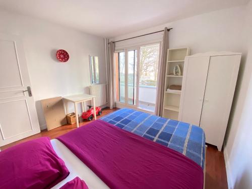 a bedroom with a bed with purple and blue sheets at Quiet Stay near Paris - Balcony & Private Parking in Châtillon